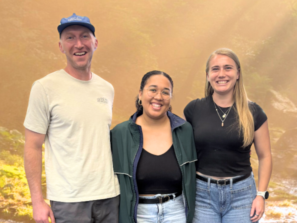 Three people photoshopped in front of a background image featuring rays of sunshine and a river.